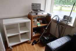 Shelves with contents as well as bread cutters and cleaning supplies